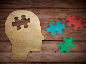 A paper head cutout with puzzle pieces representing what is CBT and how thoughts fit together